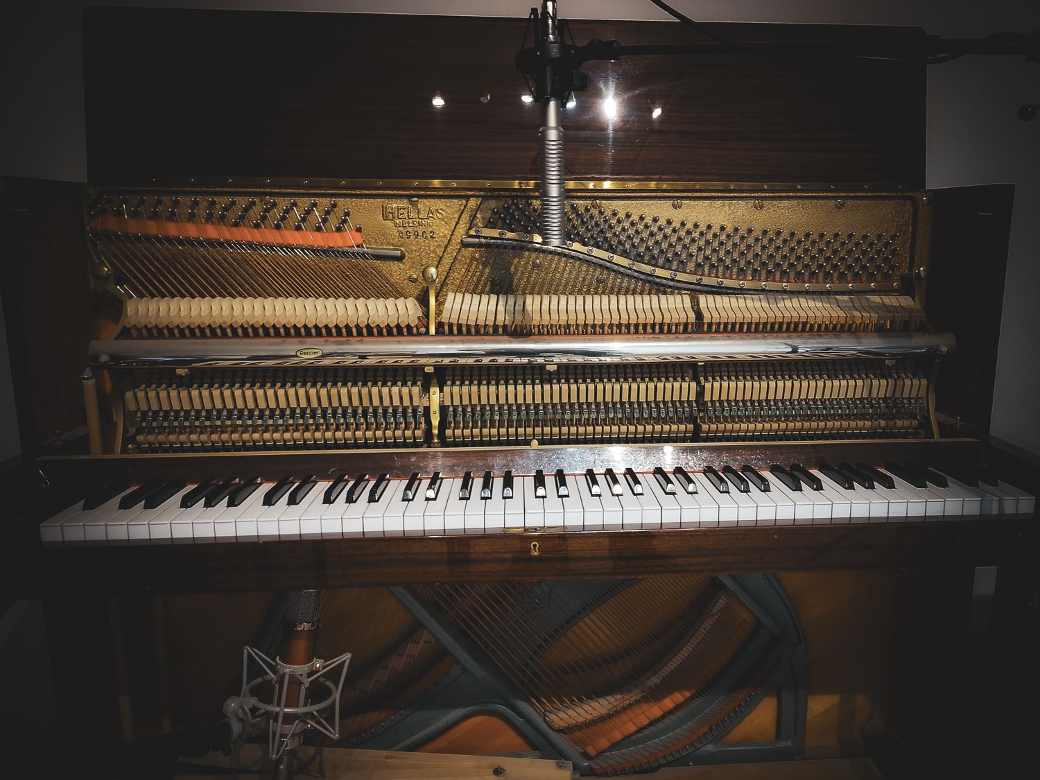 The open upright piano: strings, hammers and keyboard, with the ribbon microphone standing at the right